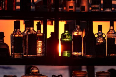 Gün batımı barın üzerinde duran şişelerin arka planında. Güneş, şişelerin parlak camından geçer. Ekran koruyucu için arkaplan resmi.