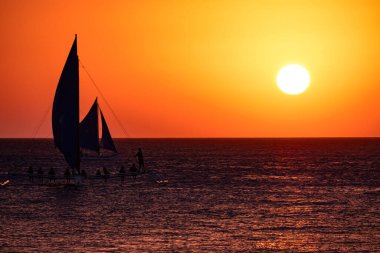 Boracay, Filipinler - 26 Ocak 2020: Barda duran şişelerin arka planında gün batımı. Güneş, şişelerin parlak camından geçer. Ekran koruyucu için arkaplan resmi.