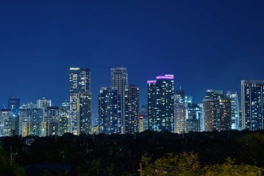 Beş yıldızlı lüks Discovery Primea otelinin havuzundan Manila 'nın gece manzarası. Güneşli bir hava. Arka planda gökdelenler.