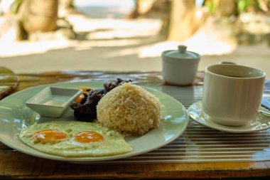 Filipinler 'in Boracay adasında beyaz kumlu sahil ve deniz manzaralı kahvaltı. Bir omlet ve beyaz bir tabakta bir fincan kahve.