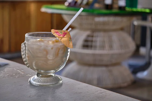 Yellow beach cocktail with a straw on the background of a sandy beach