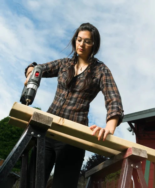 Handwerkerin benutzt Schraubenzieher, um Löcher in Holz zu bohren — Stockfoto