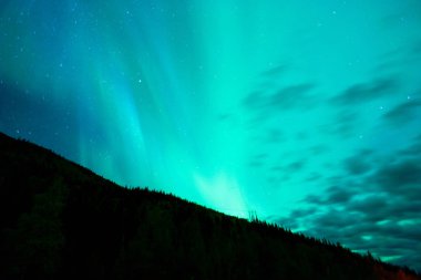Aurora Borealis bulutlar uzak Alaska ile ortaya çıkar.