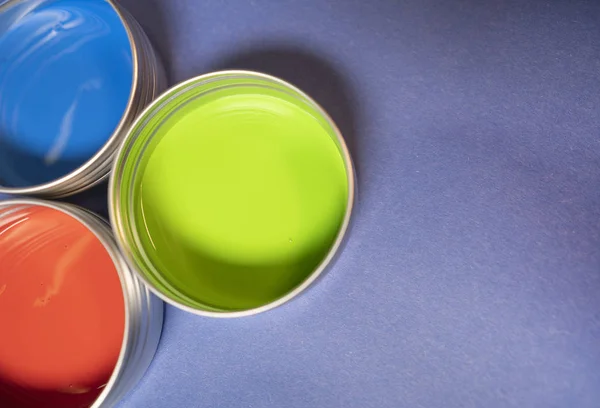 Vermelho verde e azul latas de pintura em fundo roxo — Fotografia de Stock