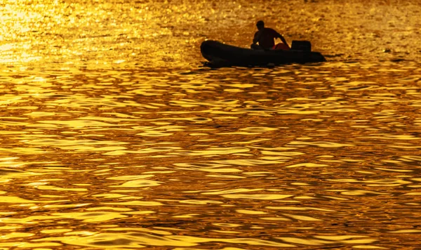 Silhouette dans un bateau au coucher du soleil doré — Photo