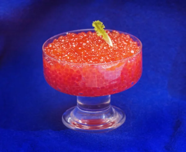 Caviar vermelho em vaso no fundo azul — Fotografia de Stock