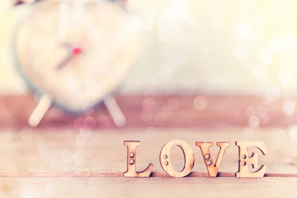Palabra Amor en mesa de madera con bokeh blanco y despertador de corazón , — Foto de Stock