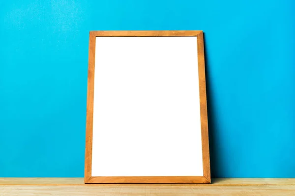 Marco de madera en blanco en la mesa de madera y la pared azul, puede agregar texto o imagen en el espacio de copia para el diseño, Plantilla de fondo de maqueta . —  Fotos de Stock