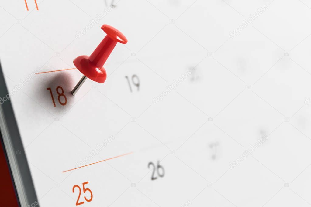 Close up red pin on white calendar.