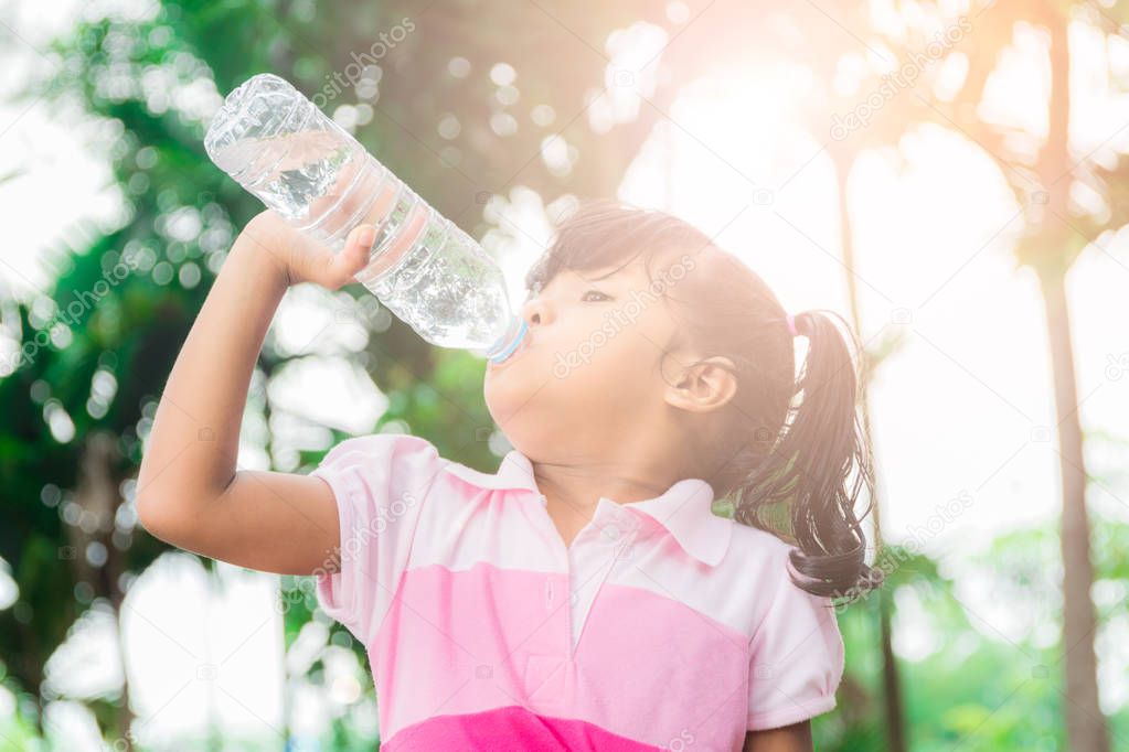 asian little girl drinking water in the forest