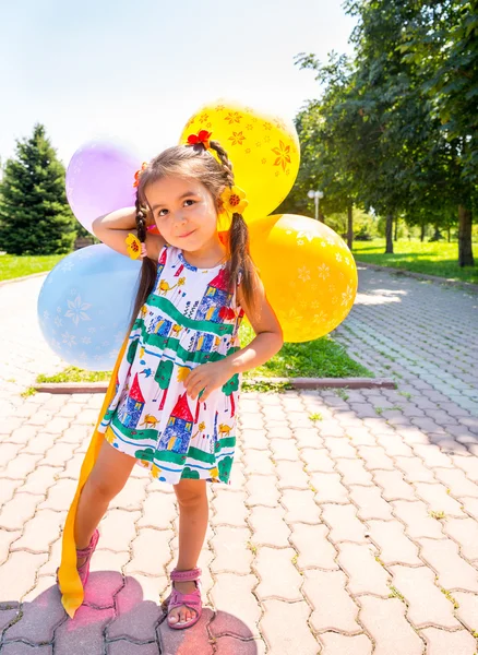 Adorable little child girl with balloons on summer nature background. — Stock Photo, Image