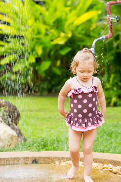 Cute little child girl in swimsuit bathing in the shower on tropical resort — Stockfoto