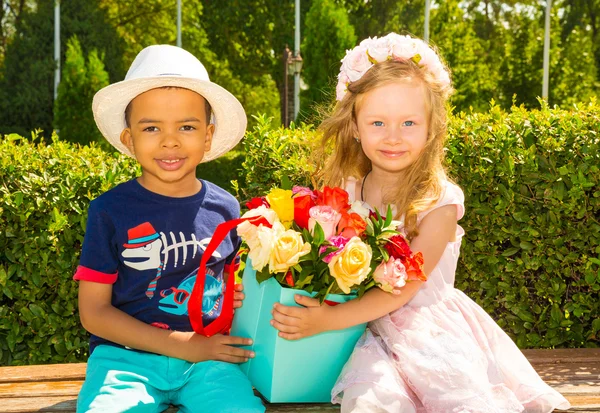 Svarta afrikanska amerikansk pojke kid ger blommor till flicka på födelsedag. Små bedårande barn i parken. Barndom och kärlek. — Stockfoto