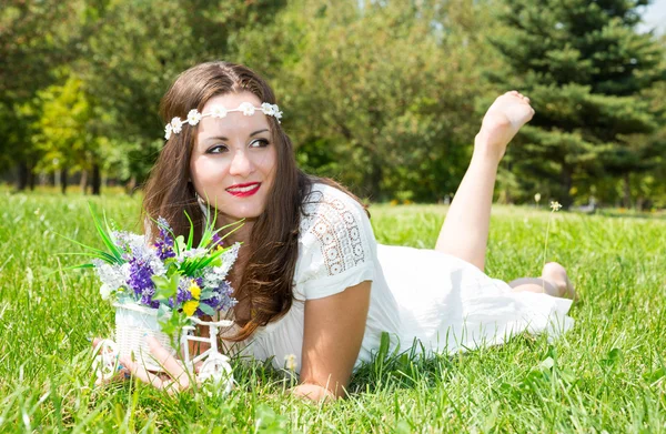 Porträt der jungen schönen lächelnden Frau mit langen Haaren und Blumen im Freien — Stockfoto