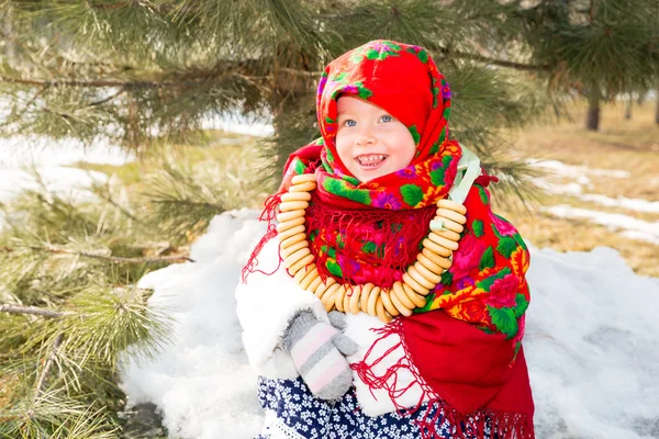 Enfant fille en russe pavloposadskie écharpe folklorique sur la tête avec impression florale et avec un tas de bagels sur fond de neige. Portrait de fille habillée dans le style russe — Photo