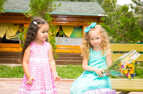 Две подружки. Очаровательные маленькие дети с букетом цветов на день рождения. Парень в парке — стоковое фото