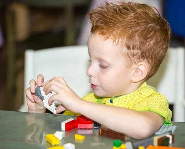 Chłopiec dziecko gra z lego Konstruktor w wieku przedszkolnym przy stole w przedszkolu — Zdjęcie stockowe