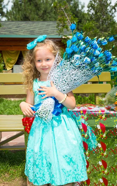 Όμορφο κορίτσι ευτυχισμένο παιδί με ένα μπουκέτο λουλούδια την ημέρα των γενεθλίων στο πάρκο. Γιορτή έννοια και παιδικής ηλικίας, αγάπη — Φωτογραφία Αρχείου
