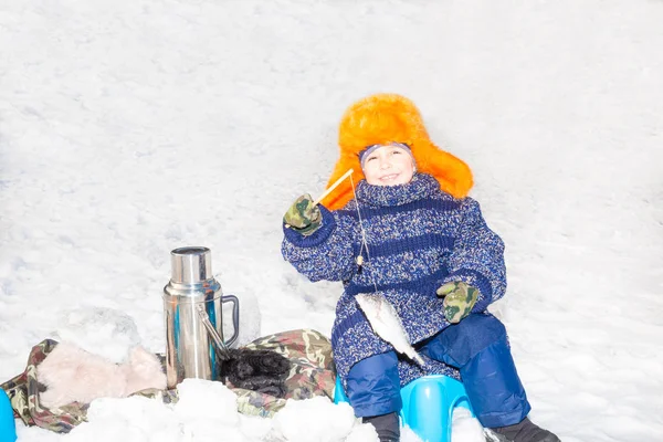 Pojke barn fångat en fisk på ett bete på fiske vinter. Vintersport och kokplatta — Stockfoto