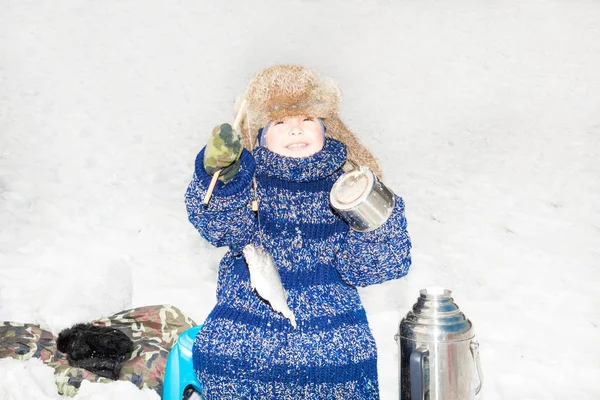 Pojke barn fångat en fisk på ett bete på fiske vinter. Vintersport och kokplatta — Stockfoto