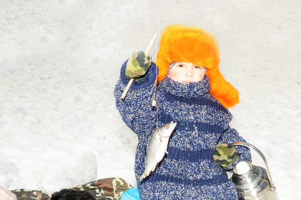 Garçon enfant attrapé un poisson sur un appât sur l'hiver de pêche. Sport d'hiver et plaque de cuisson — Photo