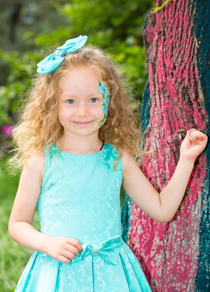 Menina feliz bonita criança com aqua make-up no aniversário no parque. Conceito de celebração e infância, amor — Fotografia de Stock