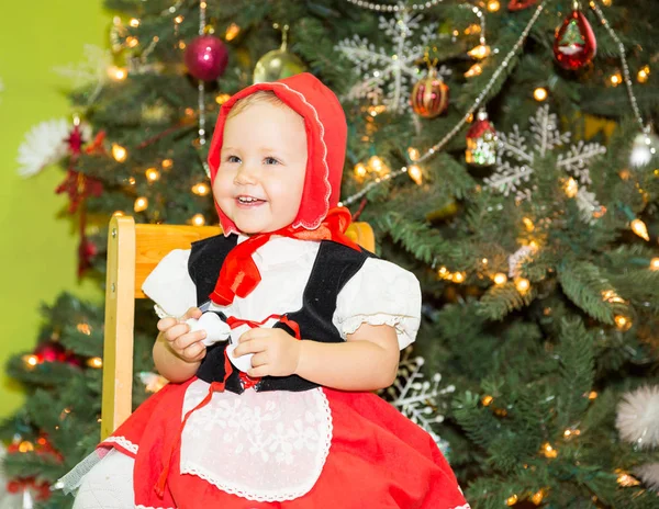 Muotokuva tyttö lapsi puku punainen hattu jouluksi noin kuusen koristeltu. Lapsi lomalla uusi vuosi — kuvapankkivalokuva