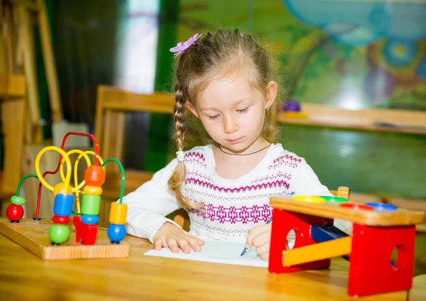保育室でカラフルな鉛筆で描いている愛らしい子女の子。子供のモンテッソーリ幼稚園のクラスで幼稚園に. — ストック写真