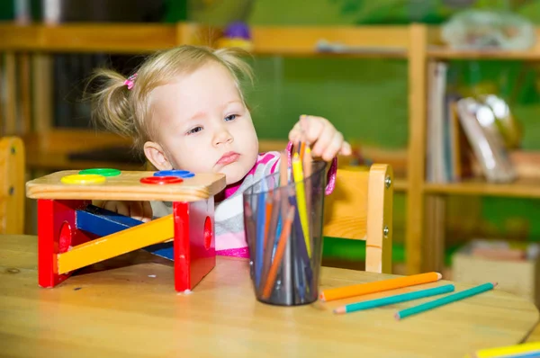 Urocze dziecko dziewczynka rysunek z kolorowych ołówków w żłobku. Dziecko w przedszkolu w klasie przedszkola Montessori. — Zdjęcie stockowe