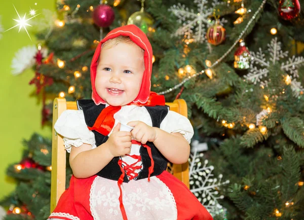 Muotokuva tyttö lapsi puku punainen hattu jouluksi noin kuusen koristeltu. Lapsi lomalla uusi vuosi — kuvapankkivalokuva