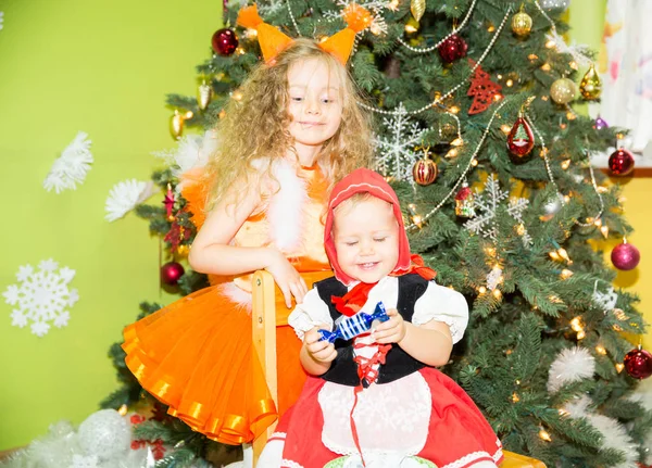 Retrato de crianças meninas em um terno esquilos em torno de uma árvore de Natal decorada. Crianças em férias ano novo — Fotografia de Stock