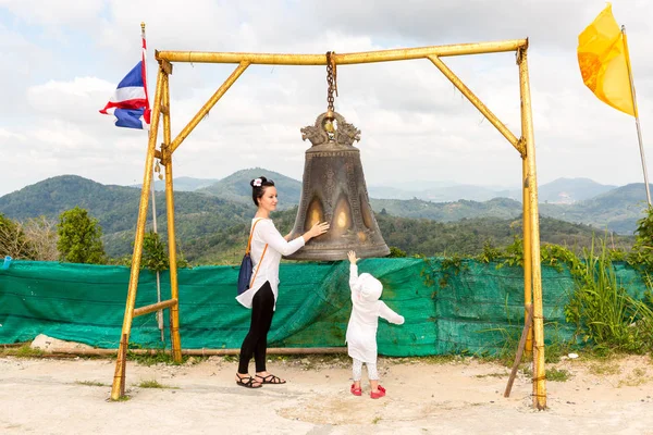 Child and mom near Thai gong in Phuket. Tradition asian bell in Buddhism temple in Thailand. Famous Big bell wish near Gold Buddha — Stock Photo, Image