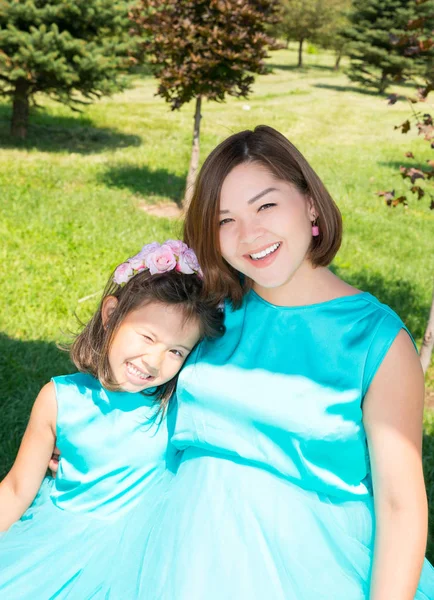 Feliz embarazada asiática mamá y el niño niña abrazando. El concepto de la infancia y la familia. Hermosa madre y su bebé al aire libre — Foto de Stock