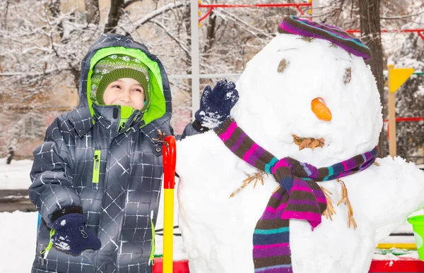 Gelukkig kind jongen spelen met een sneeuwpop op winter wandeling in de natuur. Kind met plezier bij Kerstmis buiten. — Stockfoto