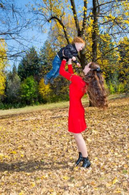 Genç anne ve oğlu sonbahar Park. mutlu bir aile: anne ve çocuk çocuk oyun sonbaharda sarılma doğa havada yürümek