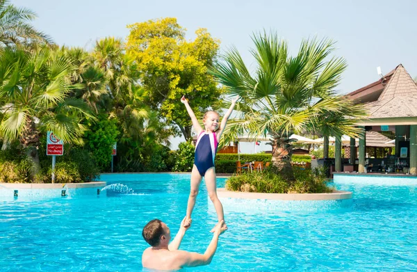 Активный отец учит дочь плавать в бассейне на тропи — стоковое фото