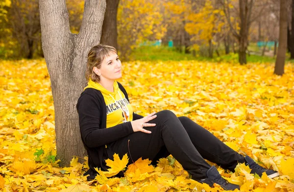 Autumn portrait of beautiful woman over yellow leaves while walking in the park in fall. Positive emotions and happiness concept. — Stock Photo, Image