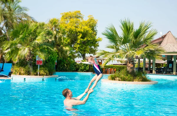 Padre activo enseñando a su hija a nadar en la piscina en Tropi —  Fotos de Stock