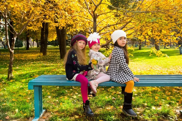 Herbstporträt schöner Kinder auf der Bank. glückliche kleine Mädchen mit Blättern im Herbst im Park. — Stockfoto