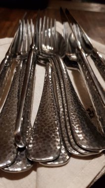 Masadaki peçeteye metal çatallar ve bıçaklar.