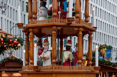 Rustic Santa Claus. Christmas funfair in Europe. Details of traditional wooden Nativity carousel with wood carving Christmas characters. Ornate New Year decorations