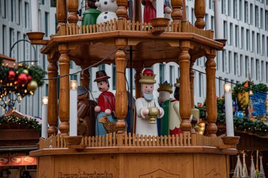 Christmas funfair in Europe. Traditional Christmas decoration. Details of wooden Christmas carousel with nativity scene and wood sculptural Christmas characters.