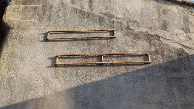 Eski binanın engebeli duvarında köşegen gölgesi olan paslı metal dikdörtgen çerçeveler. Endüstriyel mimari. Kahverengi gri tonlarında soyut bir arkaplan. Soyut arkaplan. Işık ve gölgeler. Gölge desenleri. Alışılmadık arkaplan