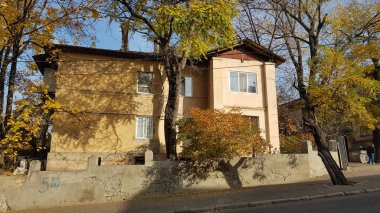 Sonbahar ağaçları ve eski Avrupa şehrinin sarı eviyle manzara. Ukrayna 'nın Odessa şehrinde kimsenin olmadığı güneşli, sakin bir manzara. Sonbahar sezonunda şehir manzarası. Işık ve gölgeler. Gölge desenleri. Şehir görünümü