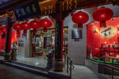 Shop. Window of Chinese store facade. Night cityscape of Shanghai city street with Lunar New Year decorations. Traditional Chinese red paper lanterns in front of showcase.
