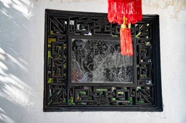 Ön planda kırmızı püsküller ve altın yüzük var. Arka plandaki ahşap çerçeveye odaklan. Çin 'in eski Şangay şehrinin Yu Yuan Bahçesi' nin klasik süslemeleri..