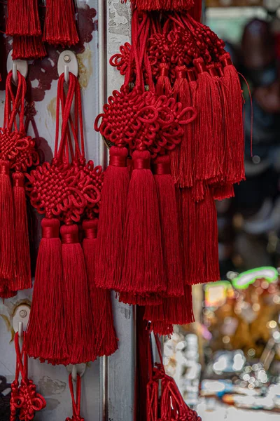 Red folk Chinese decorations with woven patterns and long tassels closeup. Texture of yarn souvenirs for Lunar New Year celebration.