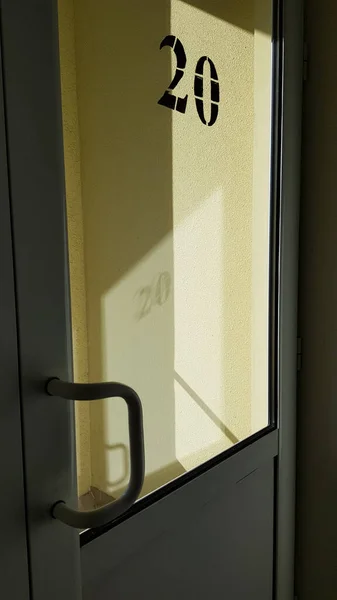 Door and light. Plastic door with glass window and blurred reflections of yellow wall and geometric shape shadows from bright sunlight. Modern architecture details.