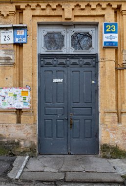 Üzerinde süslü pencereler olan eski gri ahşap bir kapı ve antika sarı tuğla bir duvar. Avrupa kentindeki eski binaların mimari ayrıntıları
