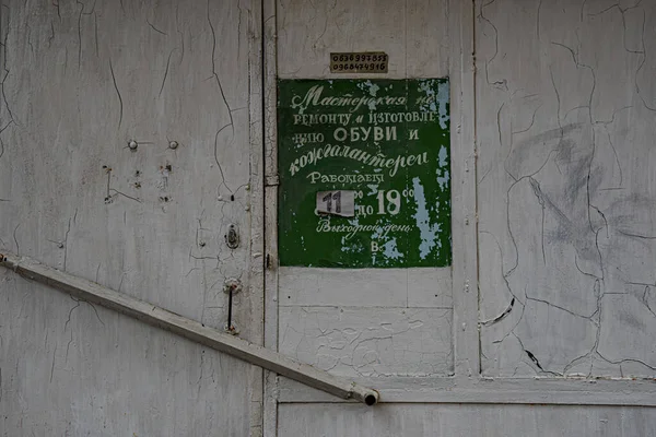 Przestarzały Zielony Szyld Staromodnym Cyrylicą Grunge Tle Zarysowanej Białej Ściany — Zdjęcie stockowe